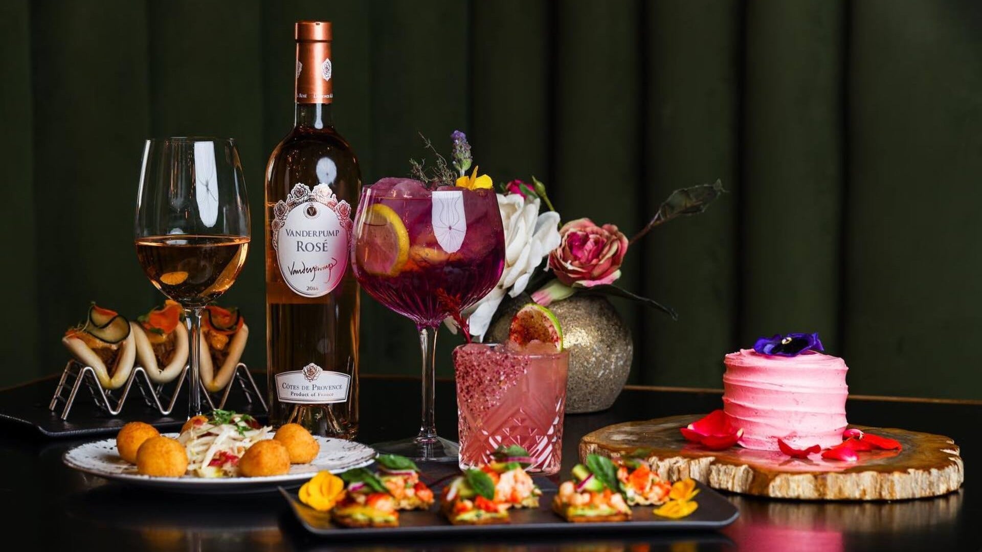 wine and rose with cake and appetizers, flowers at the back