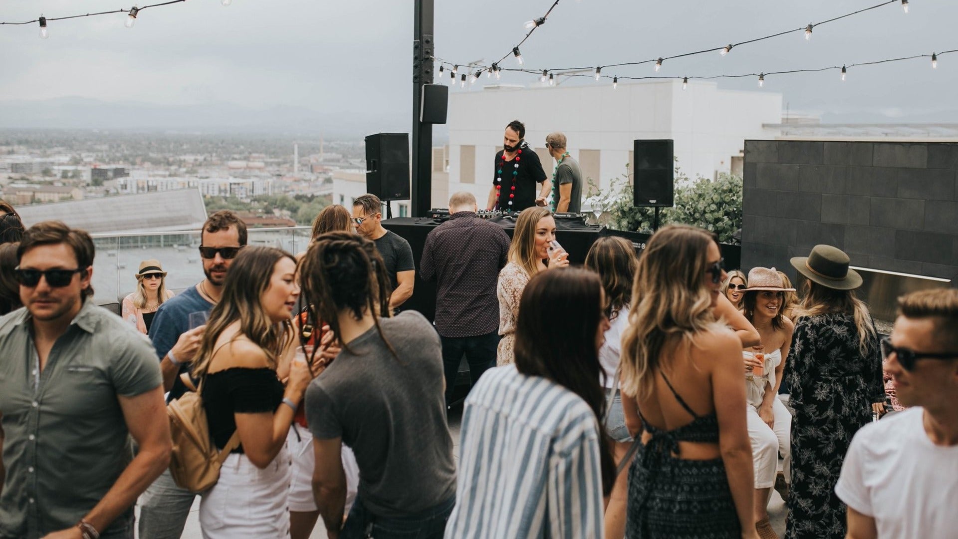 people drinking and enjotying on a rooftop bar, DJ at the back