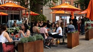 people dining outdoors, umbrellas, potted plants and trees