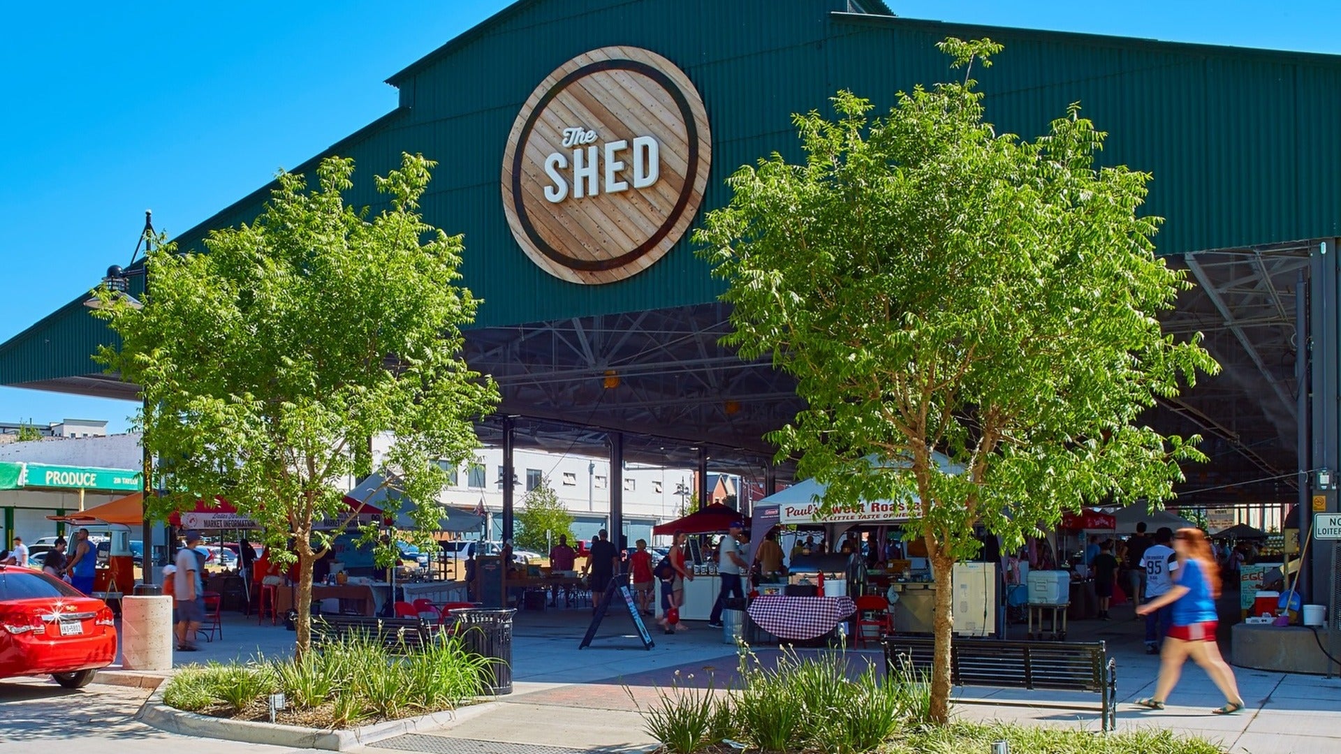 building with vendors and people shopping around, trees in front