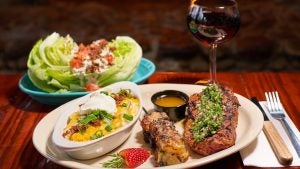 steak with cheese side dish, lettuce wrap, wine and cutleries