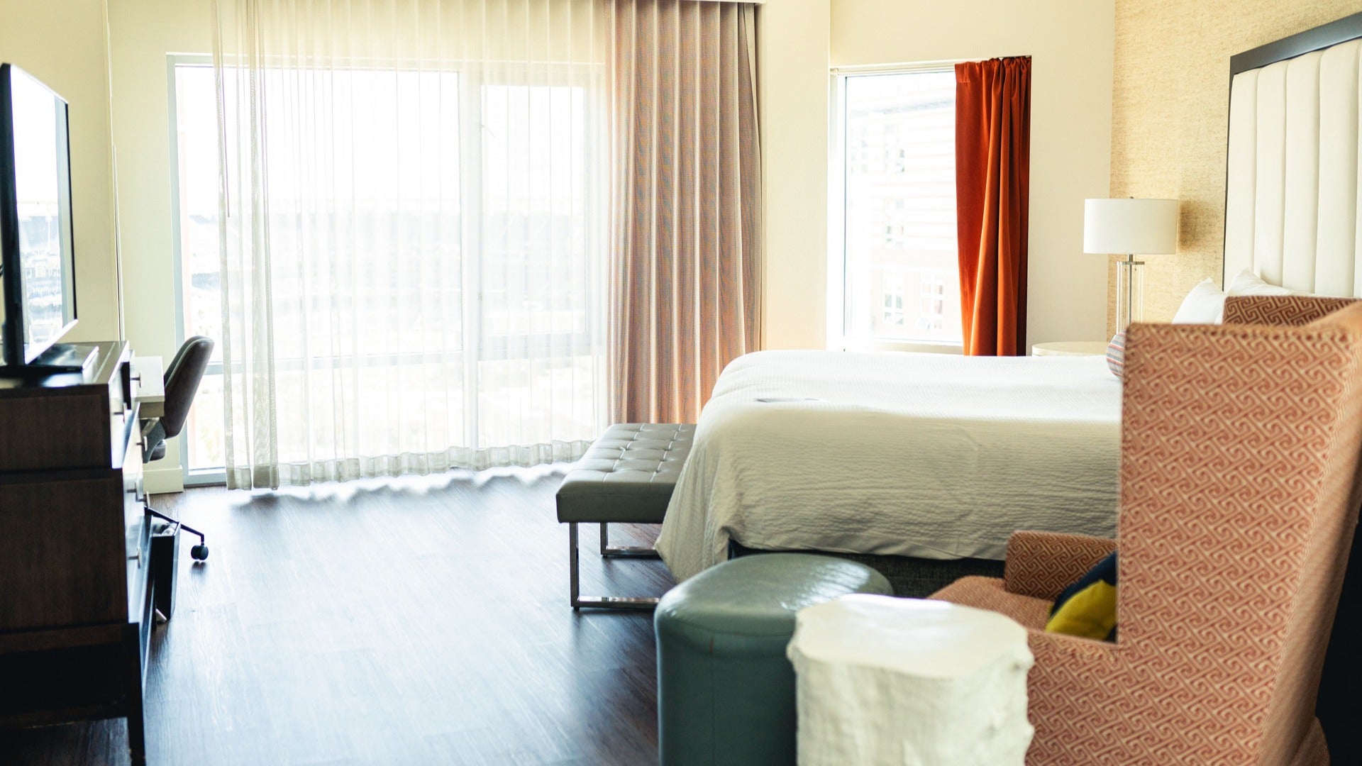 hotel room with bed, curtains, chairs, tv and lamp