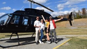 people taking a photo in front a helicopter with trees at the back