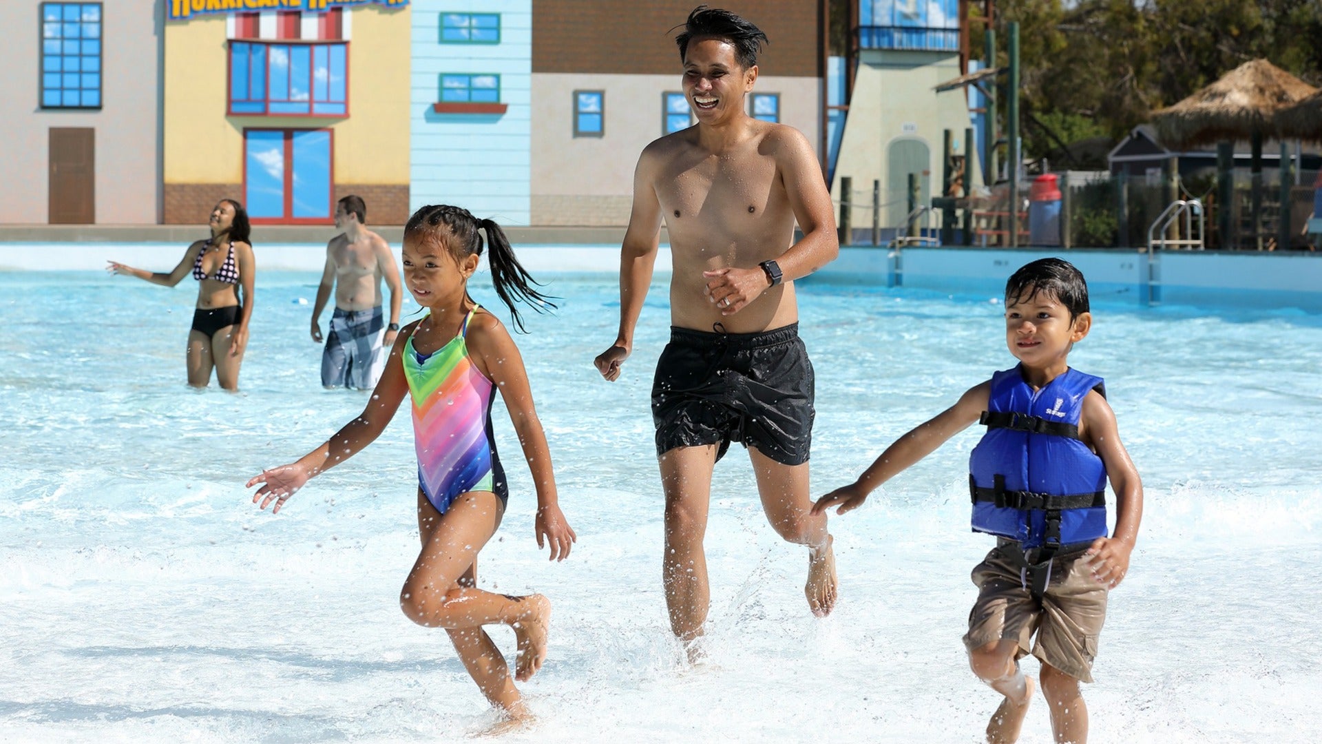 group of people running in a waterpark and splashing around the pool