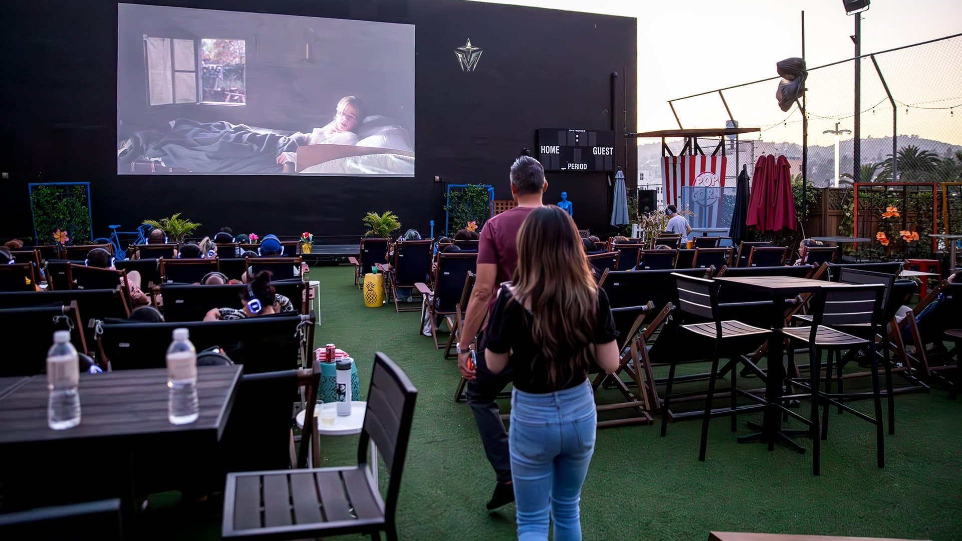 people watching an outdoor movie at a rooftop theater with buildings at the back