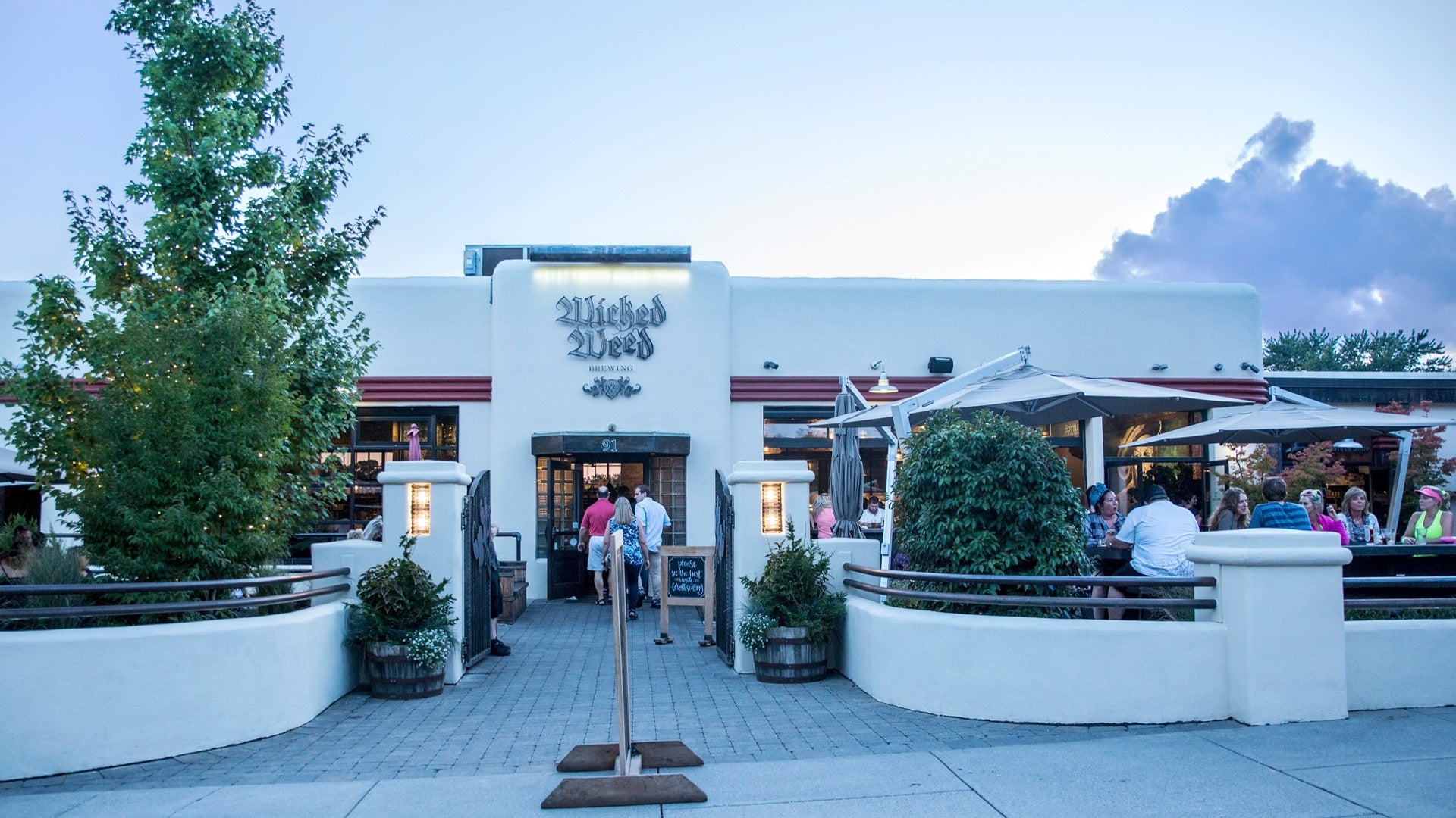 brewery exterior with people drinking, plants outside