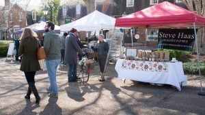 people walking around a market, stalls selling mushroom, flowers, and more