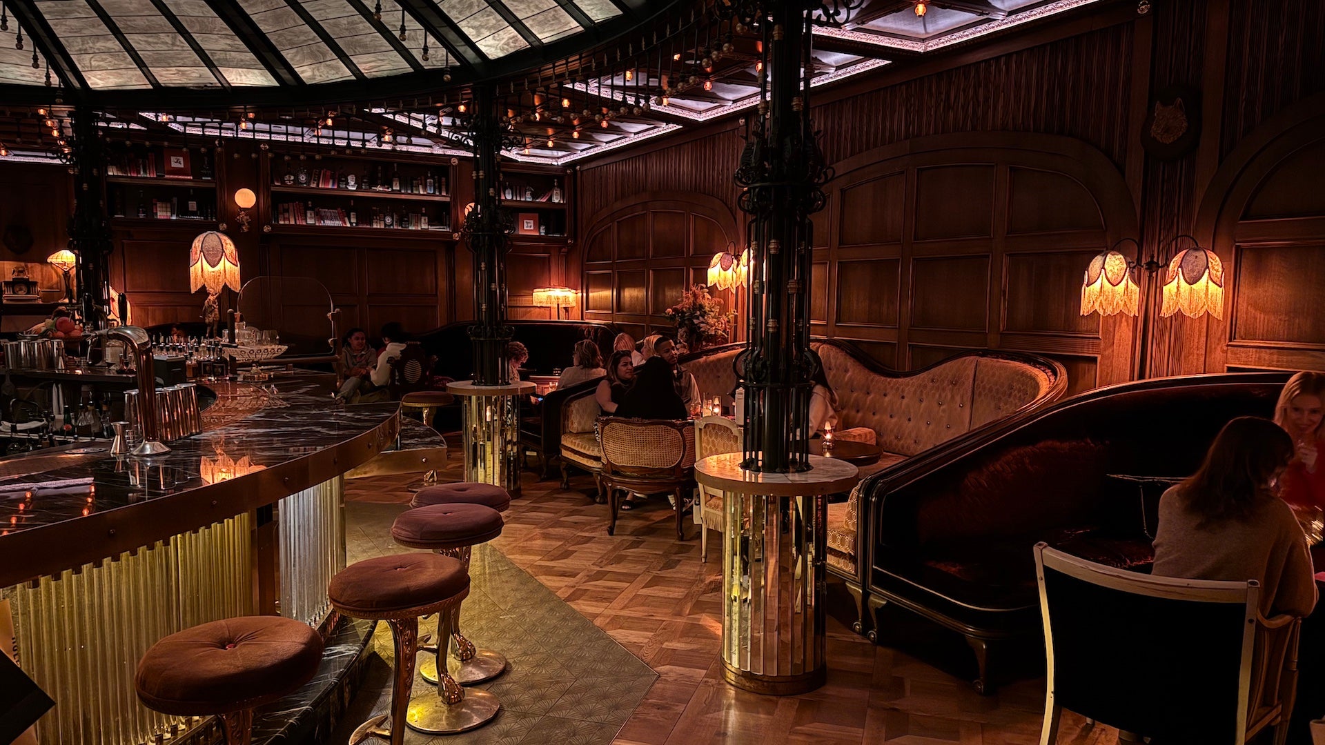 Inside a speakeasy, dimly lit with vintage and velvet furnishings