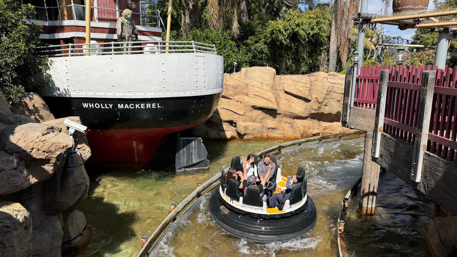 Guests on the Shipwreck Rapids ride passing a themed boat labeled Wholly Mackerel at SeaWorld San Diego.