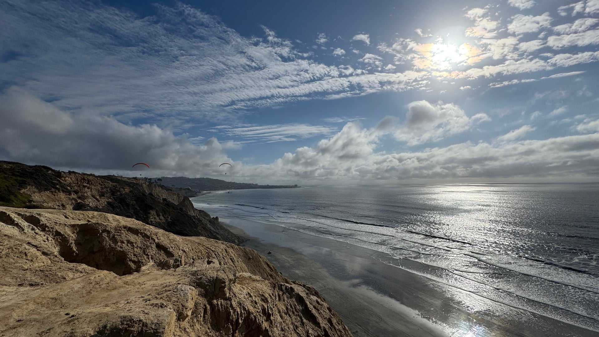 Cliffs and ocean under a cloudy blue sky