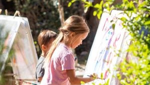 children painting in a garden, surrounded by plants