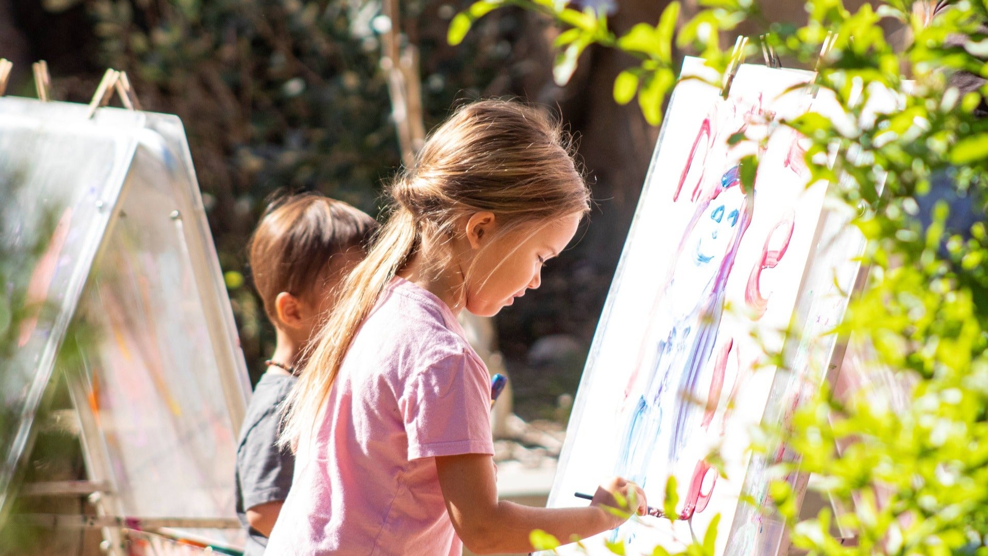 children painting in a garden, surrounded by plants