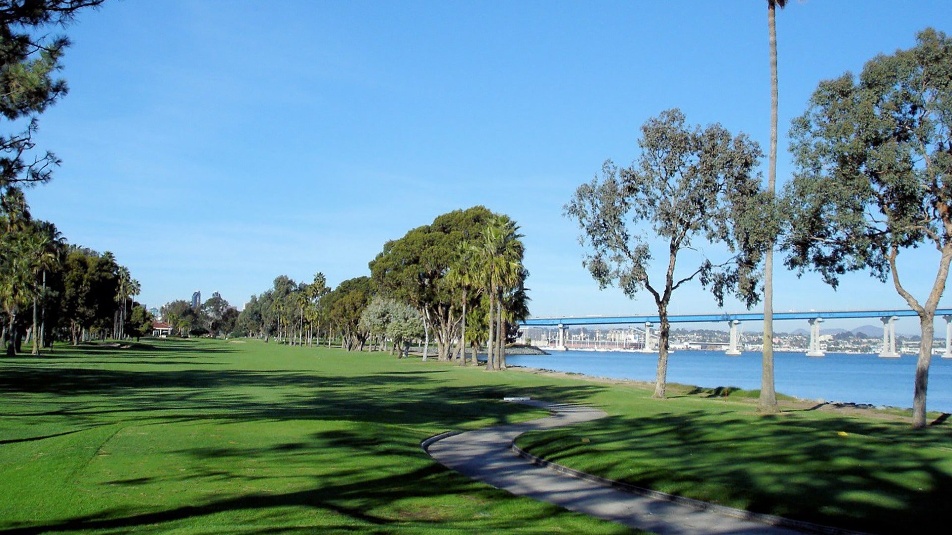 golf course with view of water and bridge at the back, surrounded by trees