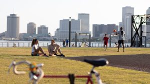 people enjoying a day in the park with river and buildings at the back