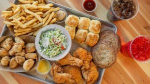 platter of chicken, fries, burger, with drinks on the side