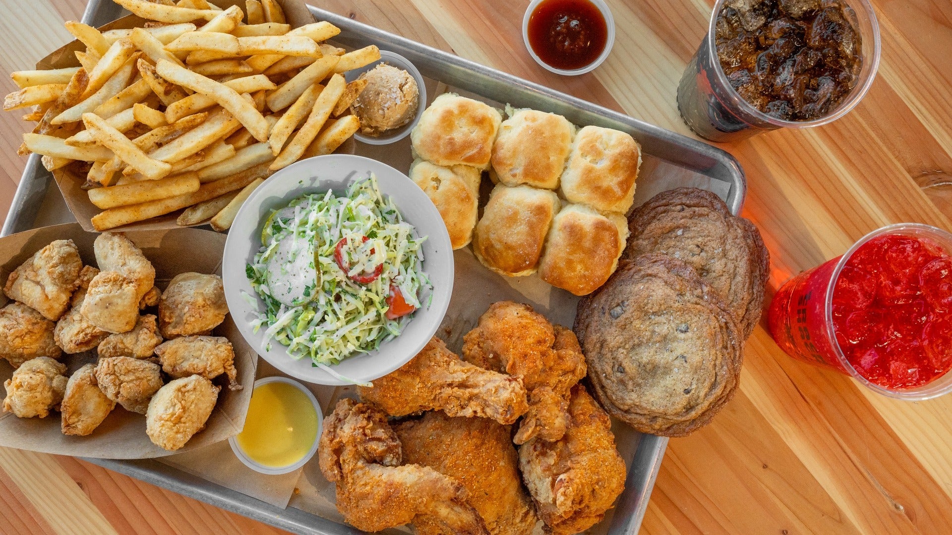 platter of chicken, fries, burger, with drinks on the side