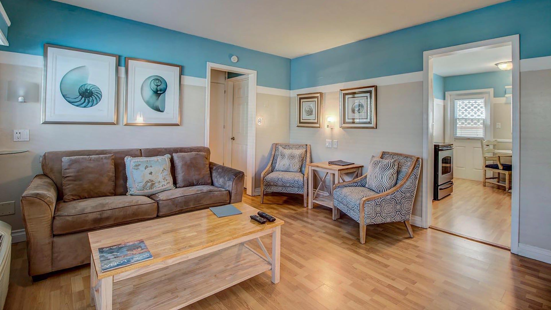 hotel room with couch, chairs, table, kitchenette and artwork