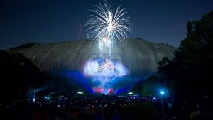 fireworks with illumination amidst mountains and crowd watching