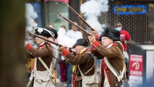 men in costume holding rifles, people watching at the back