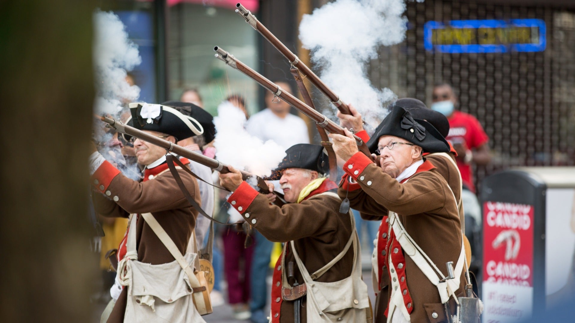 men in costume holding rifles, people watching at the back