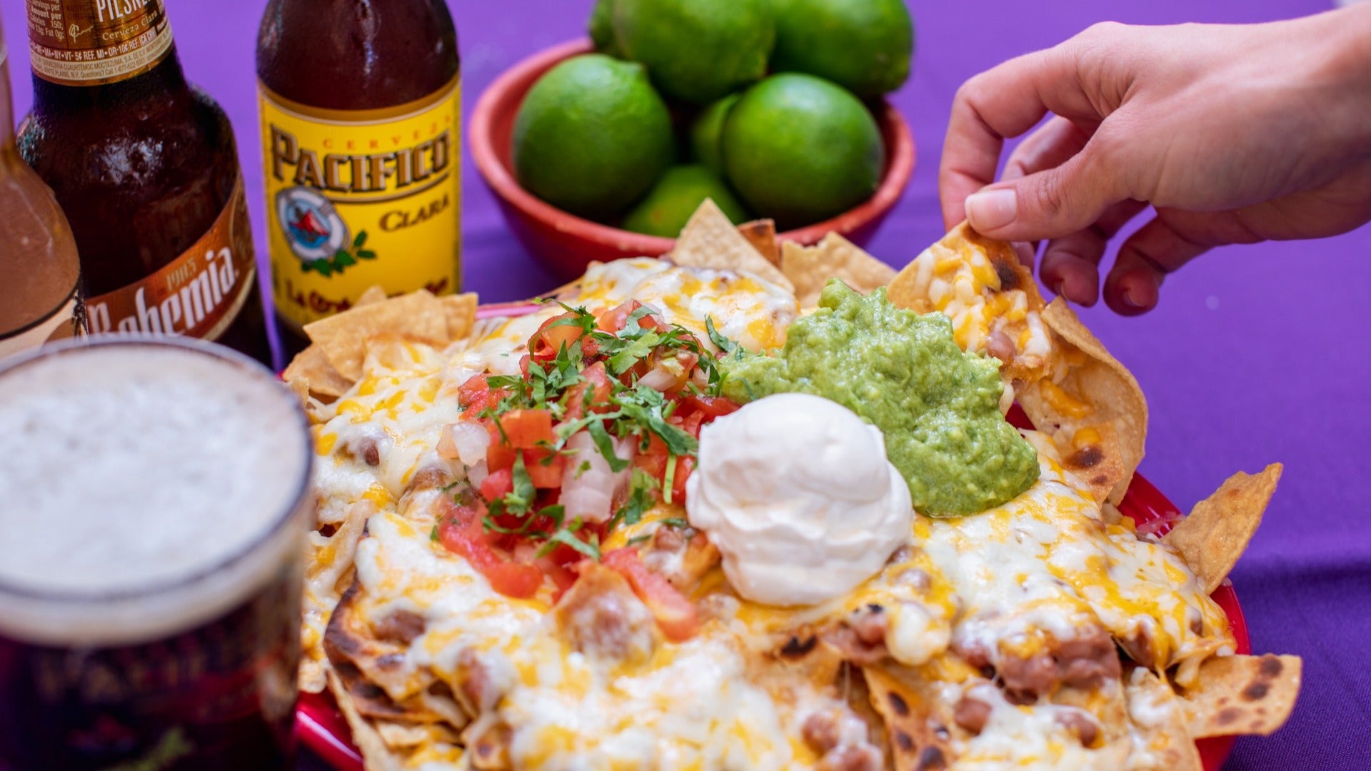 nachos with guacamole and salsa, cheese, and drinks on the side