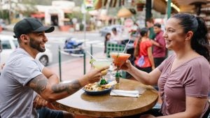 couple clinking drinks together with other people at the back