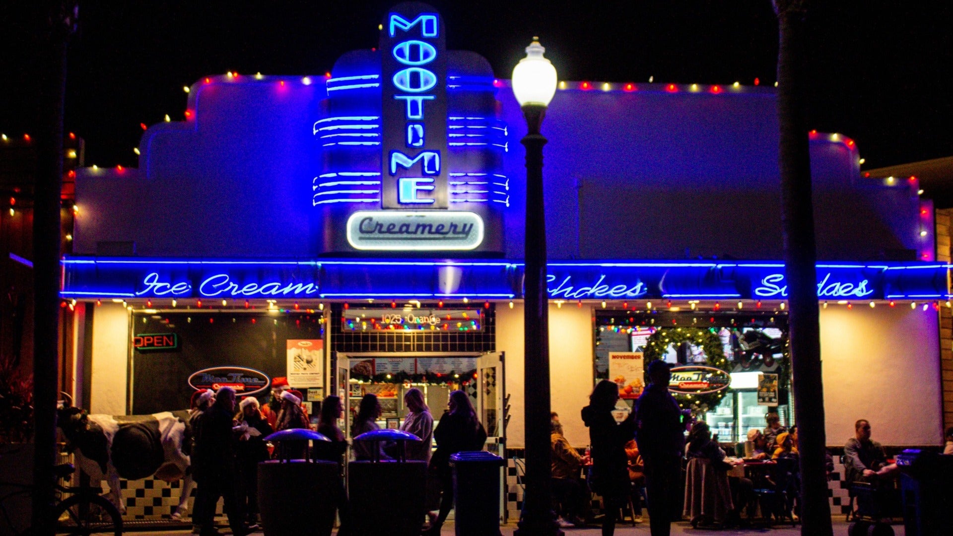 people outside an ice cream shop with christmas lights