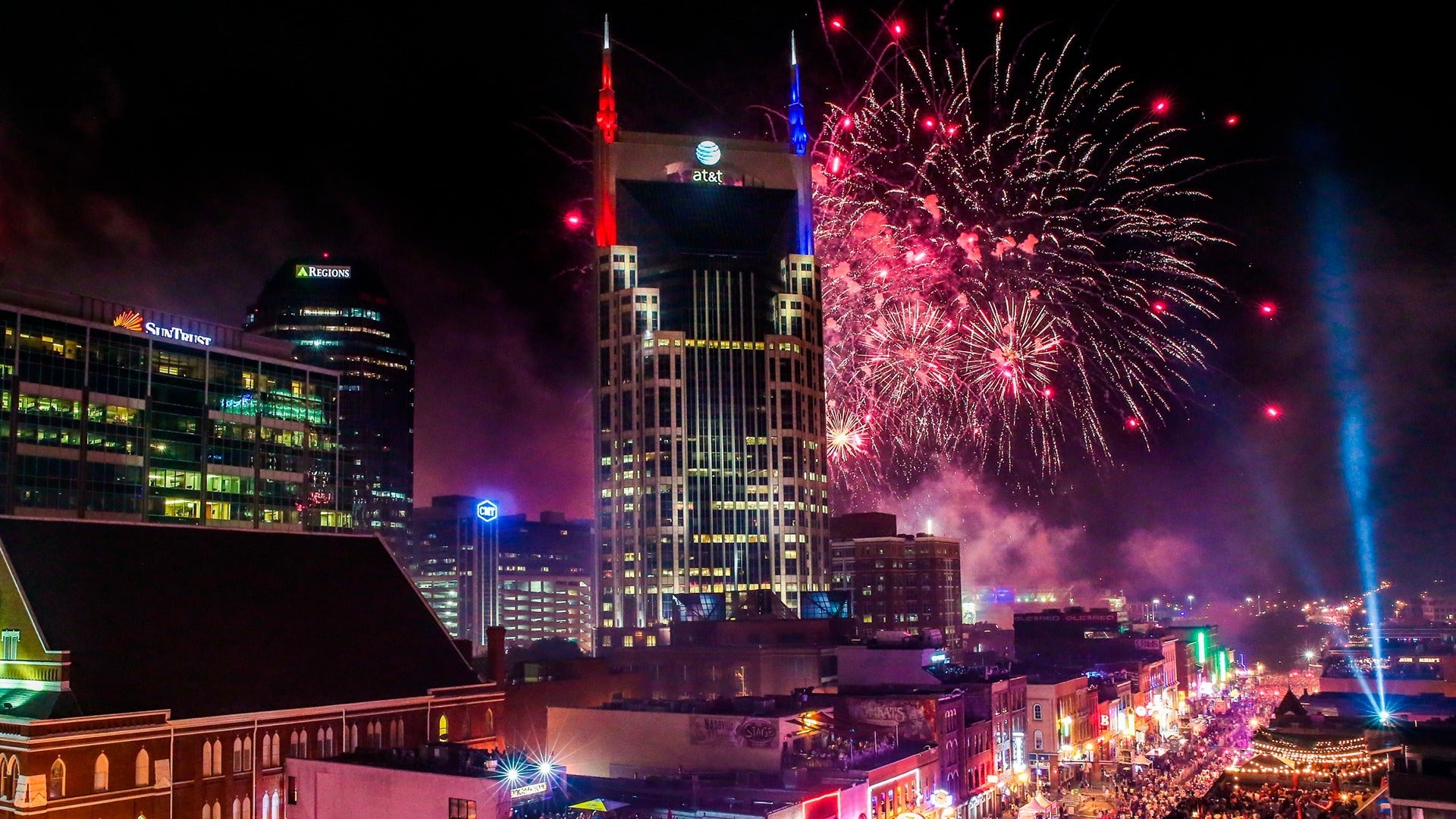 fireworks over a city with crowd below