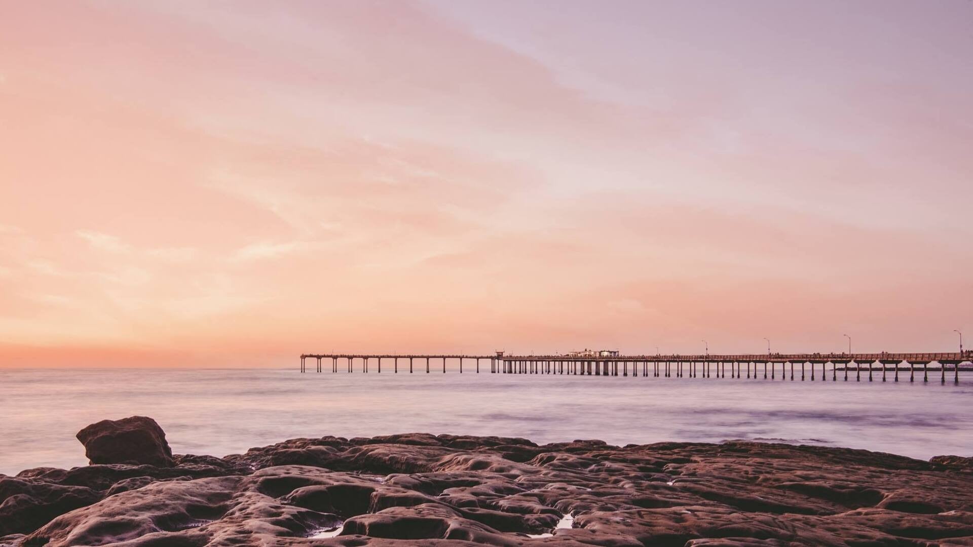 beach with rocks and pier at the back