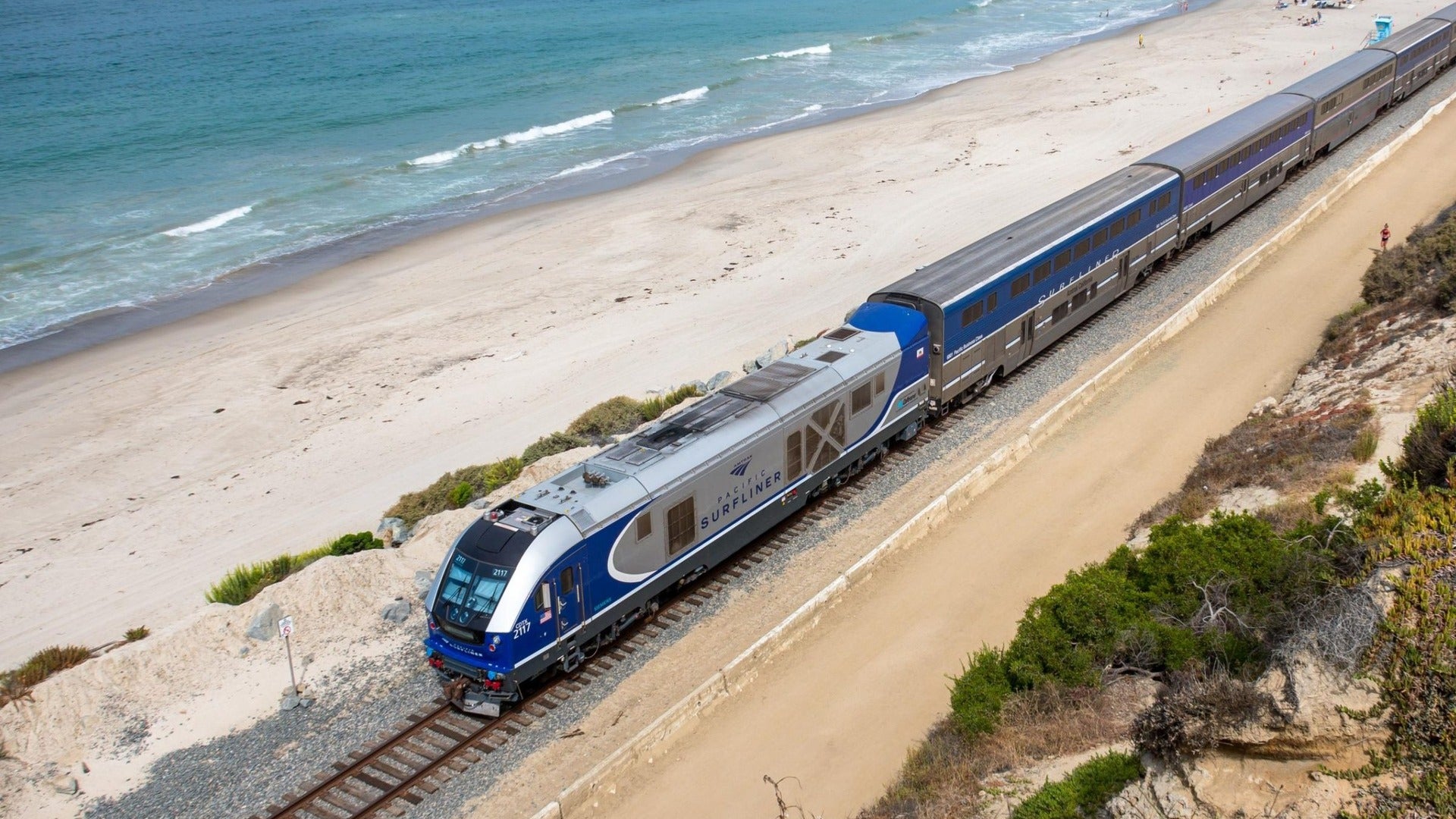 train passing by a beach and ocean on the side