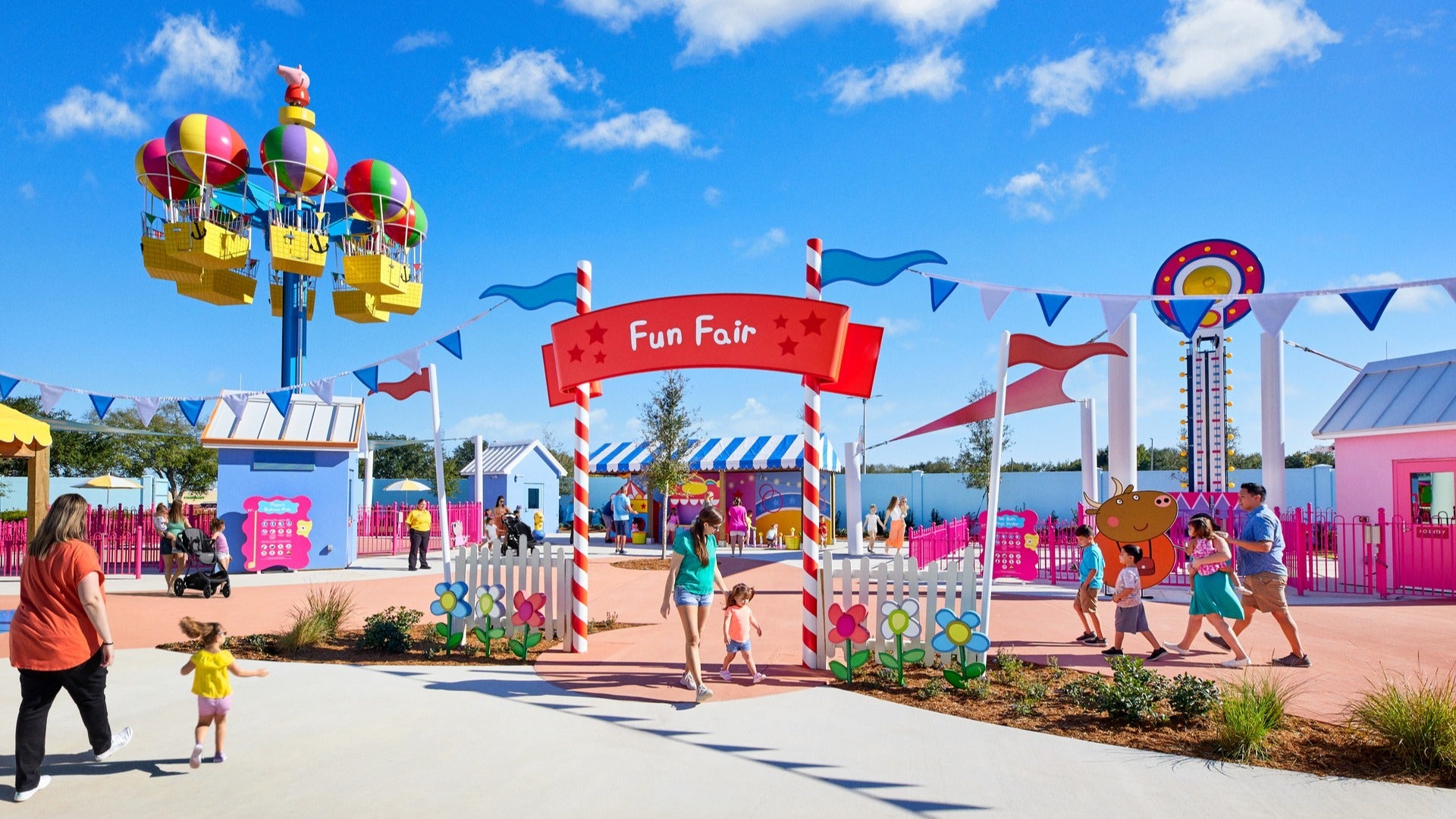 people in a theme park with colorful rides