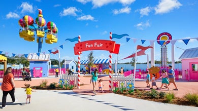 people in a theme park with colorful rides