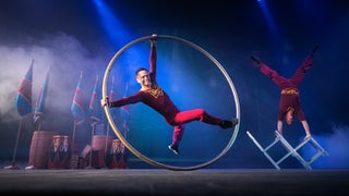 Two circus performers on a stage with their props