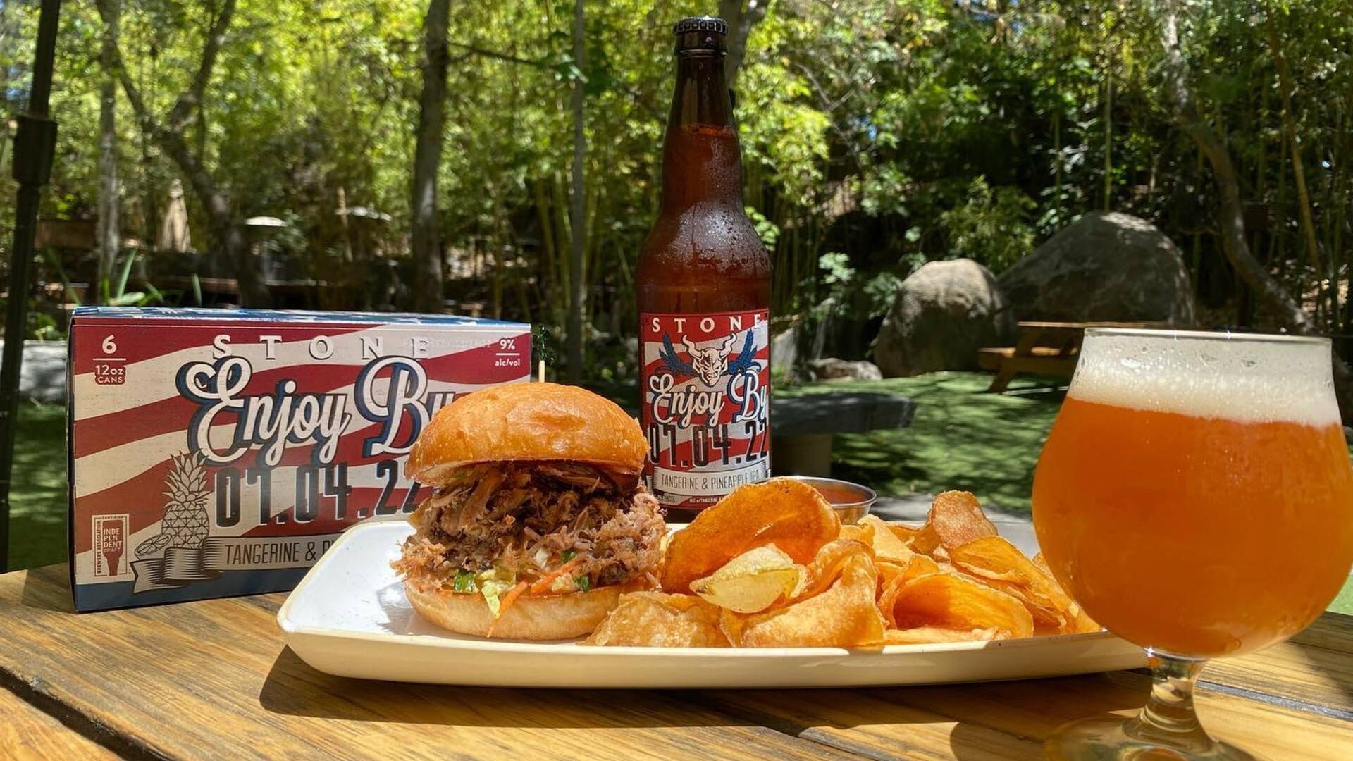 beer with burger and potato chips, trees at the back