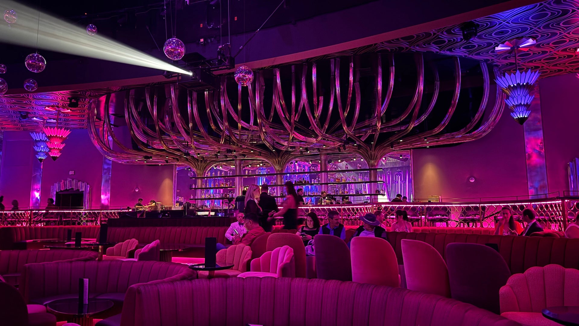 Inside a theater in Las Vegas with red velvet seating, pink and blue lighting and maximalist vintage vibes