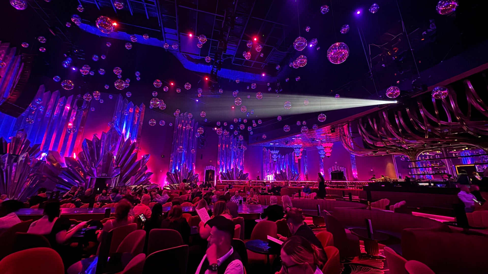 Inside a theater in Las Vegas with red velvet seating, pink and blue lighting and maximalist vintage vibes