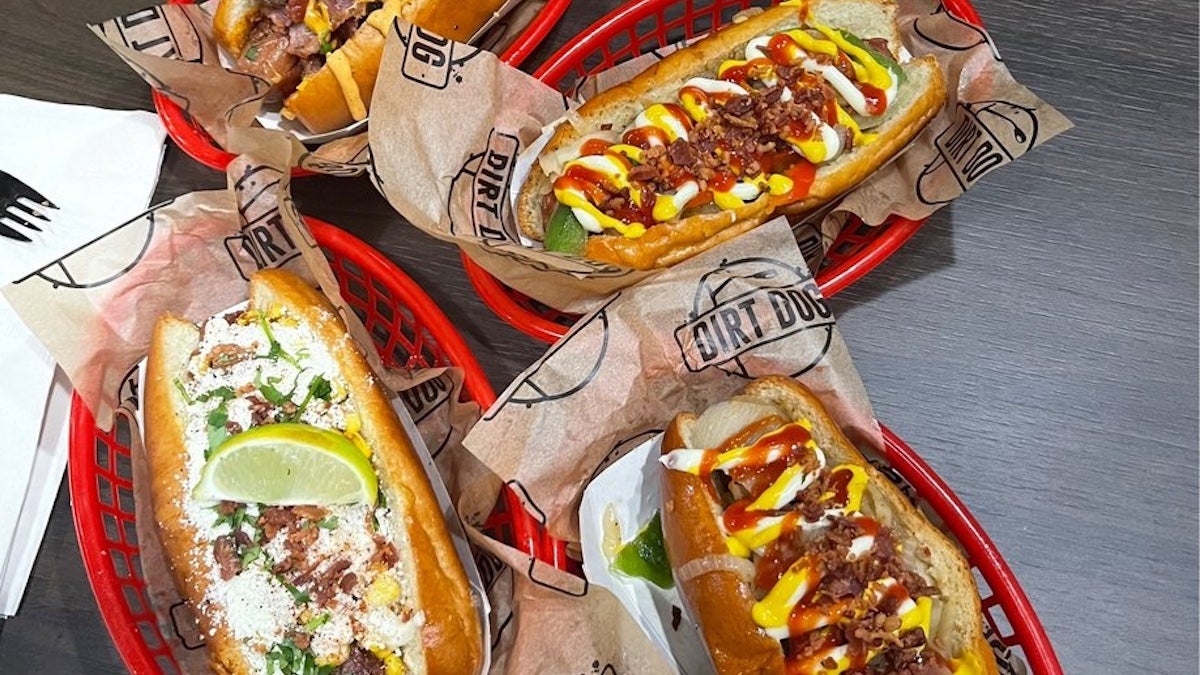 Four gourmet hotdogs on red baskets