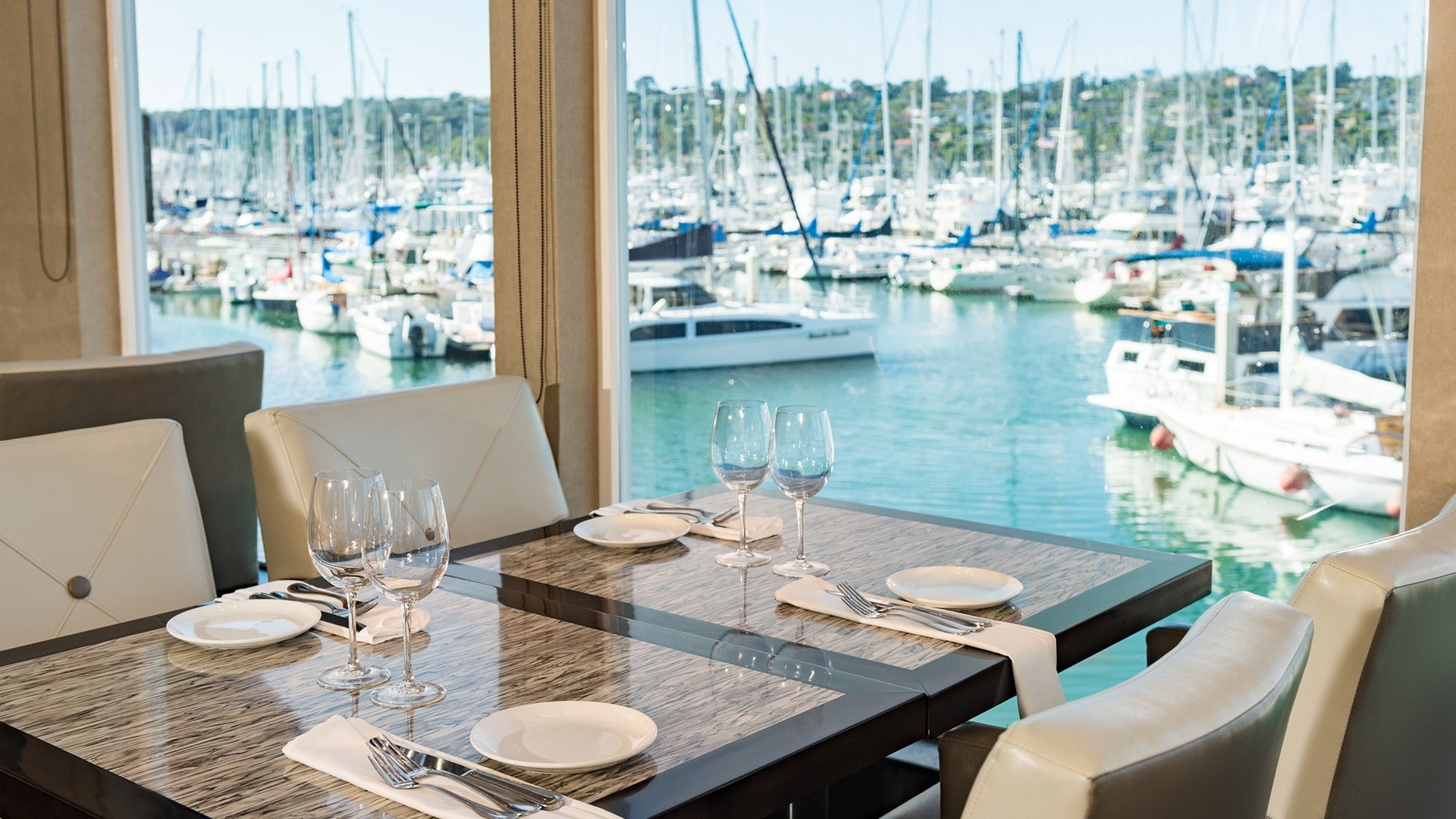 dining table with plates and glasses overlooking a marina