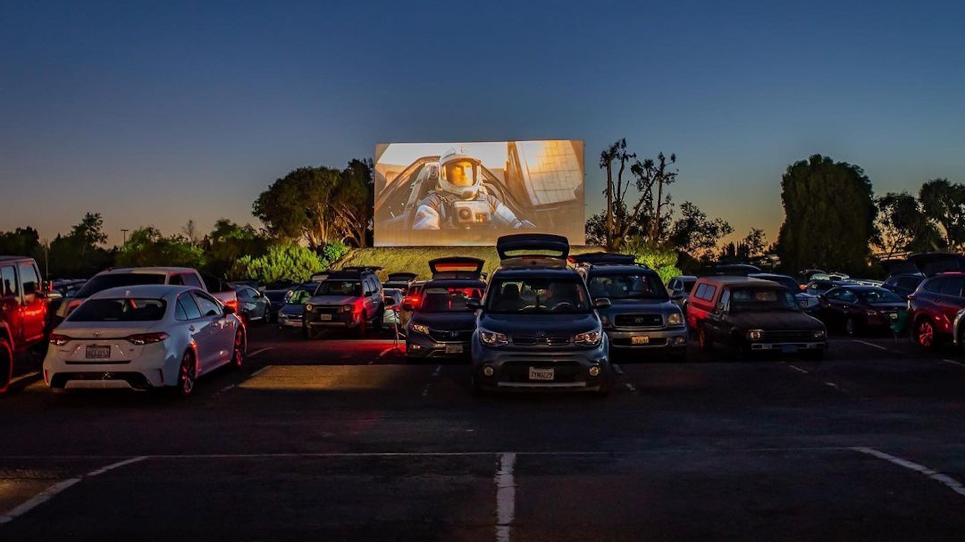 cars in front of a big screen at night