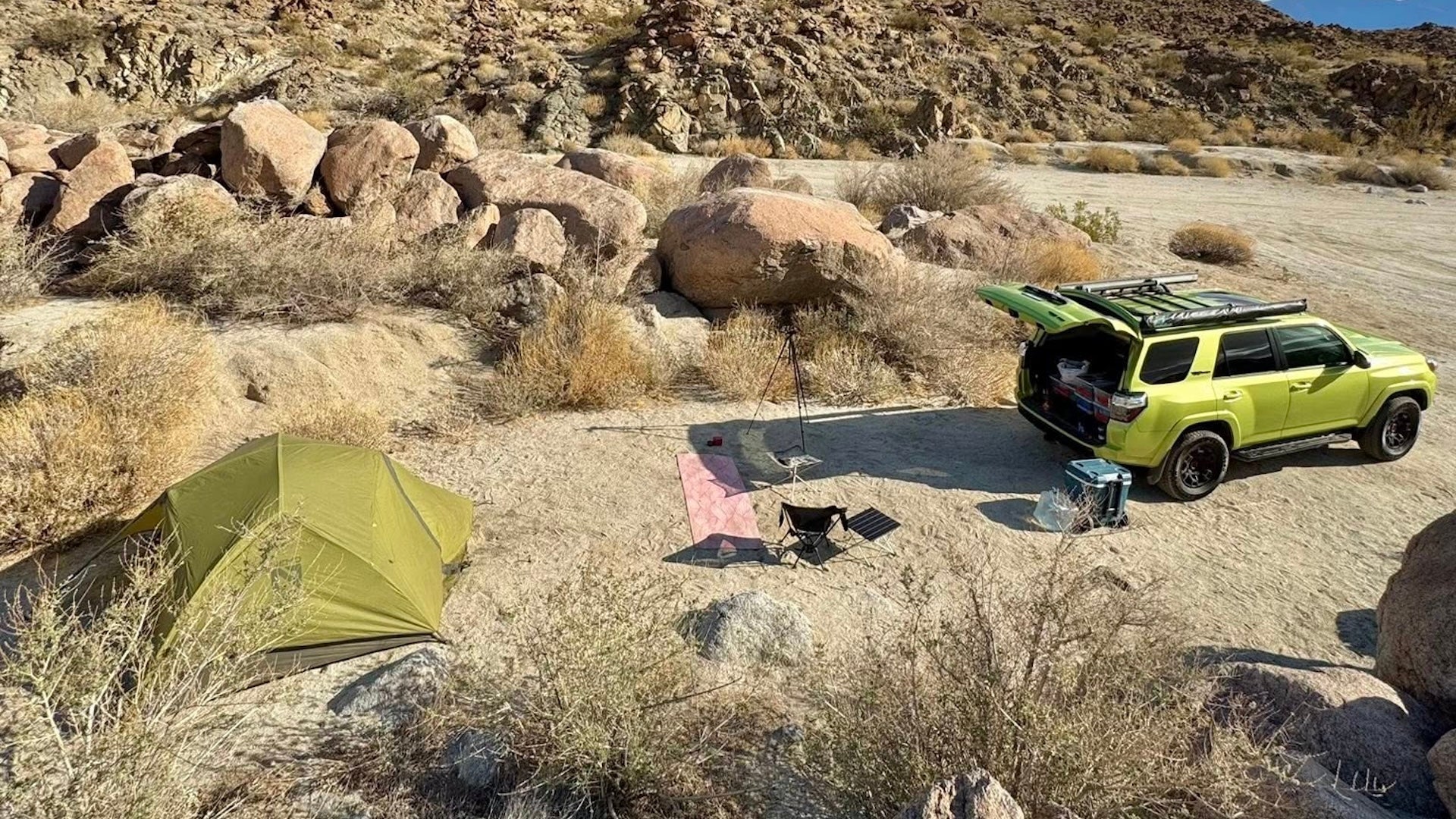 a green tent with a green car in a desert camping