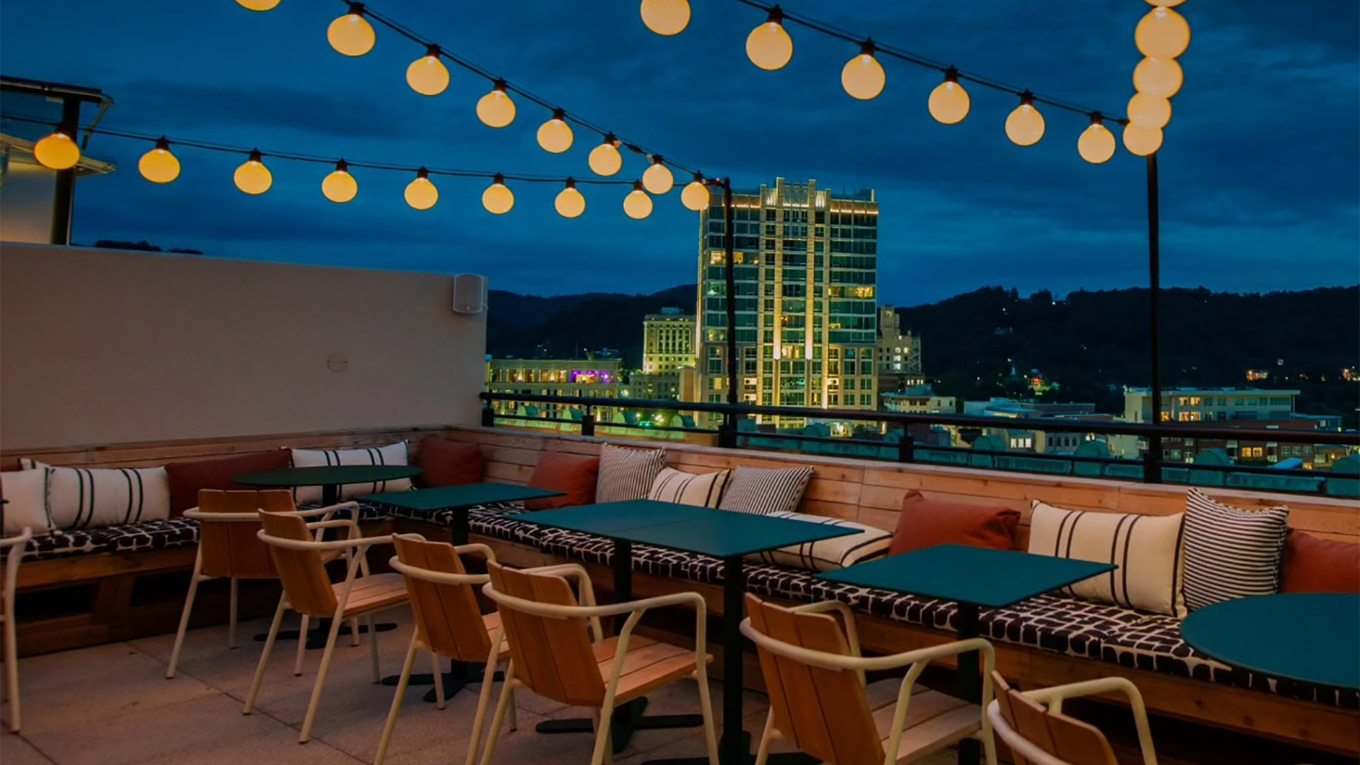 rooftop bar with tables and chairs and a city view