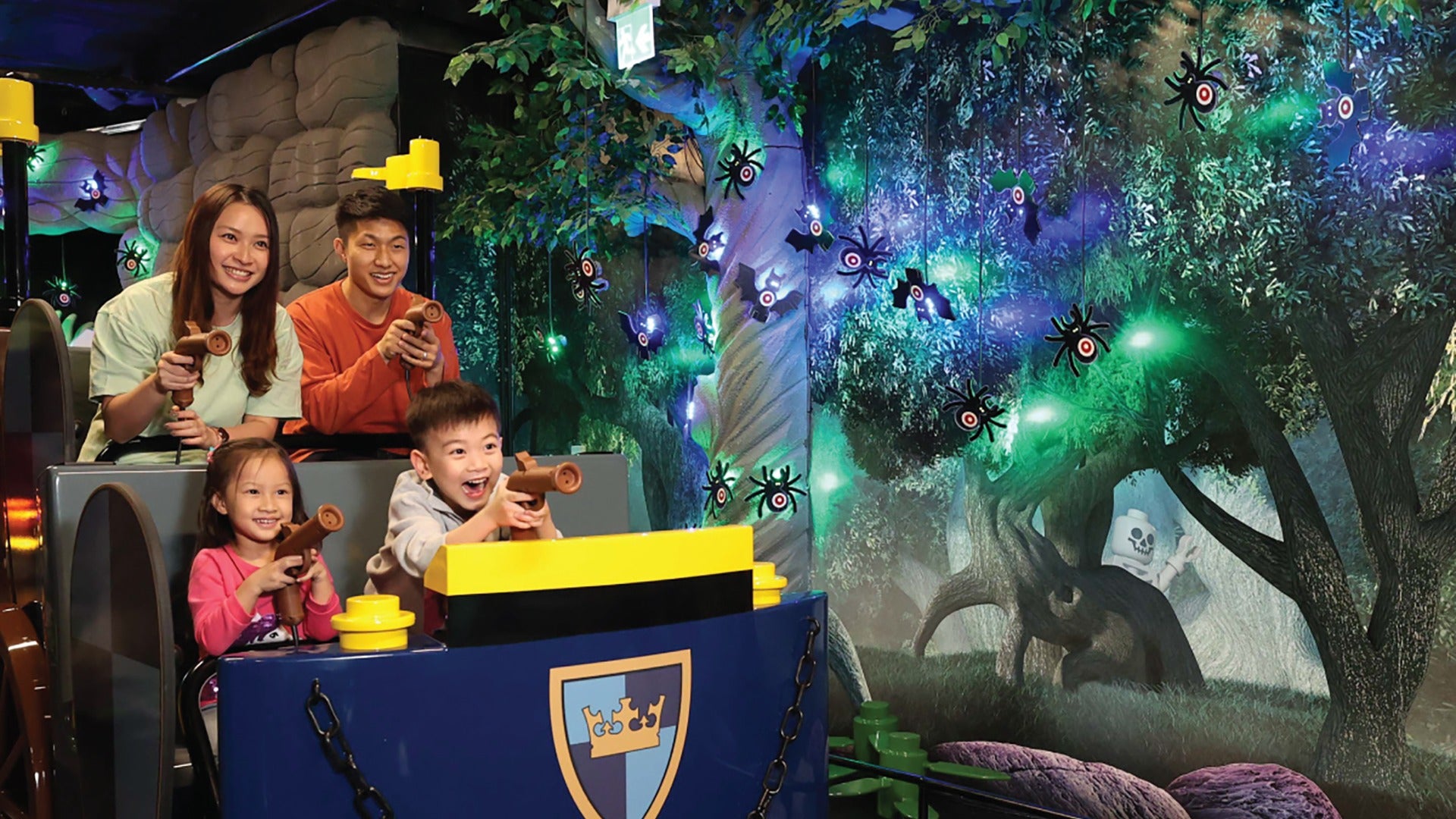 family on an indoor attraction ride with spiders and water guns