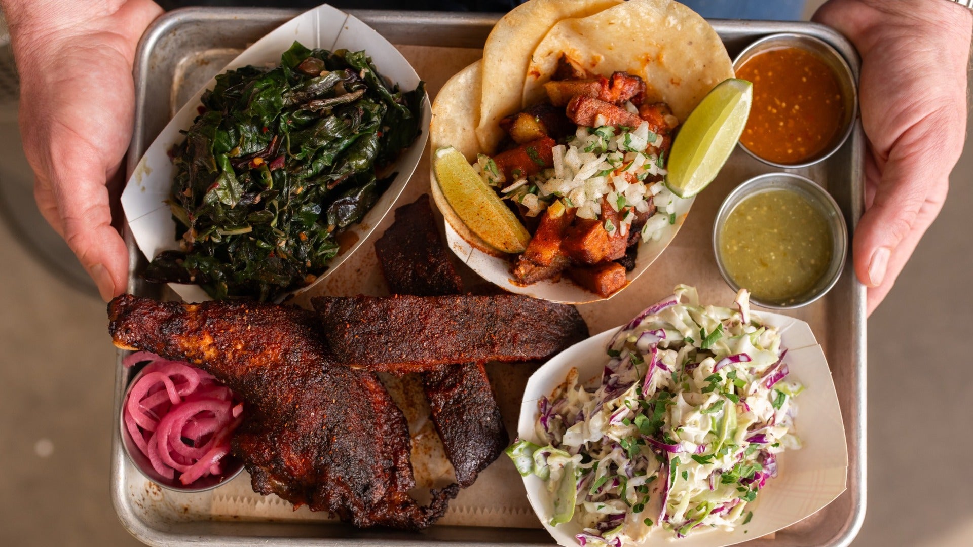 assortment of meat, taco, coleslaw, and sauces on a tray