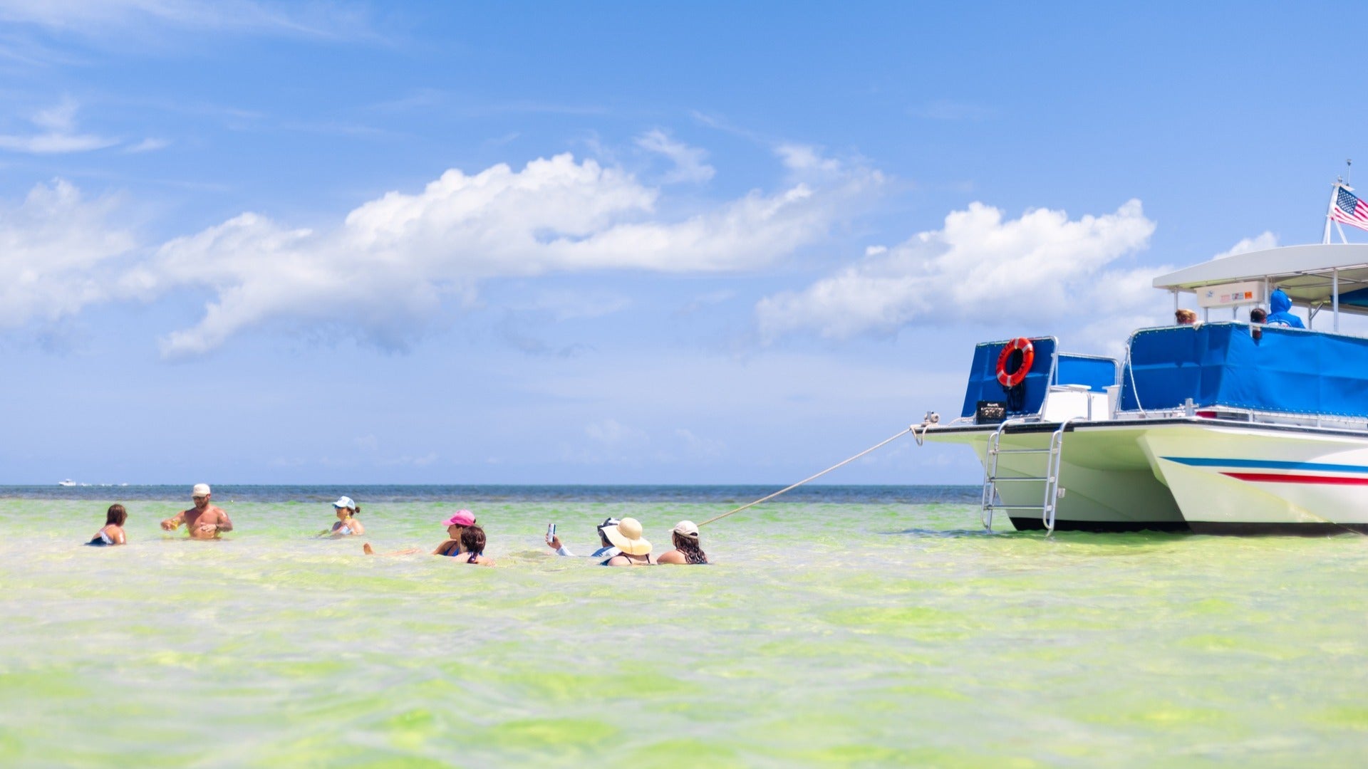 people swimming on a sand bar along a boat tour