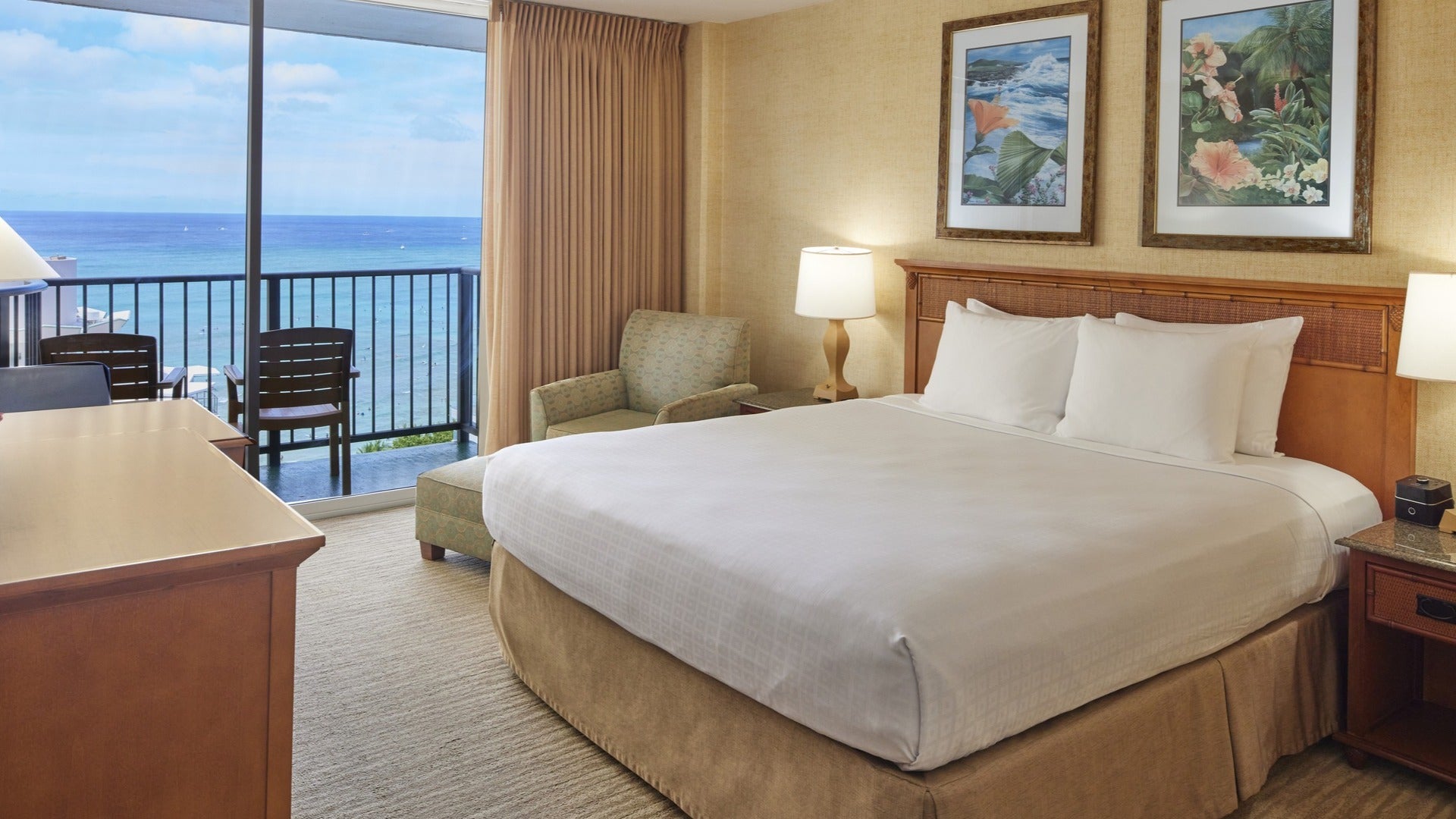 hotel room with bed and artwork, lamps, and balcony