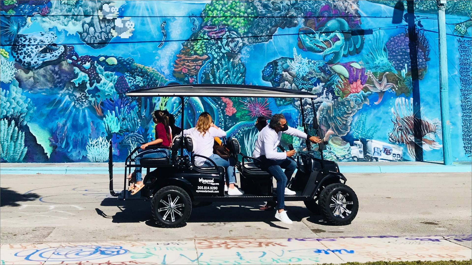 people in an ArtWalk riding a golf cart