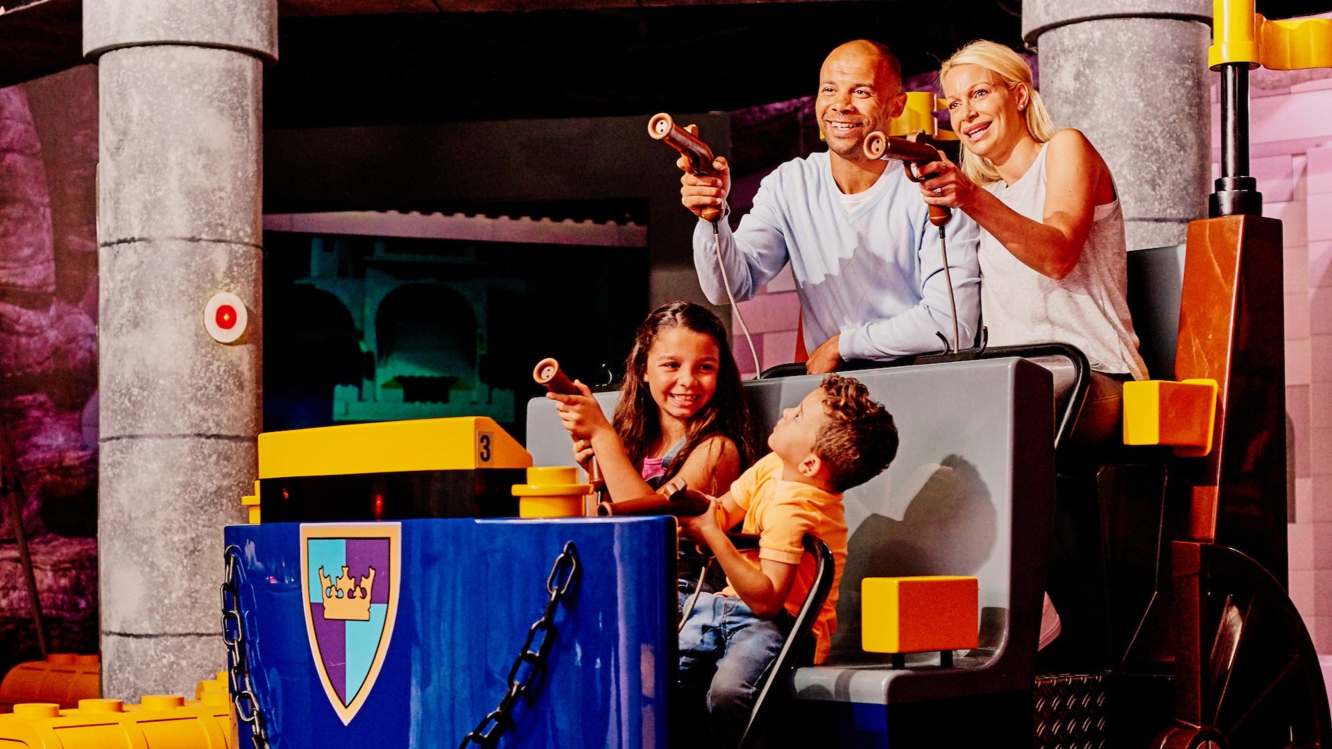 family playing on an indoor ride with water guns