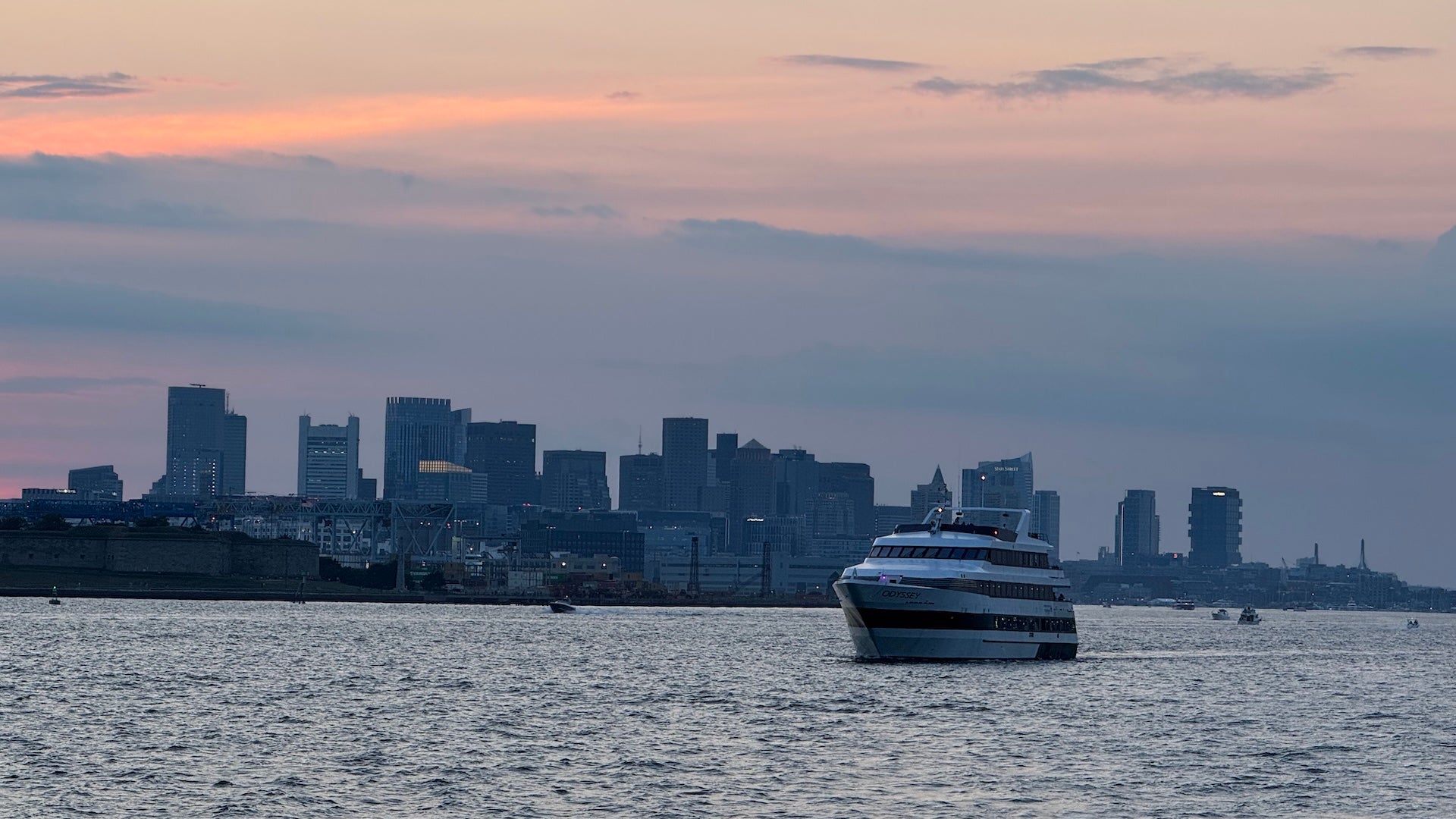 Boat on the harbor with downtown Boston in the background at sunset