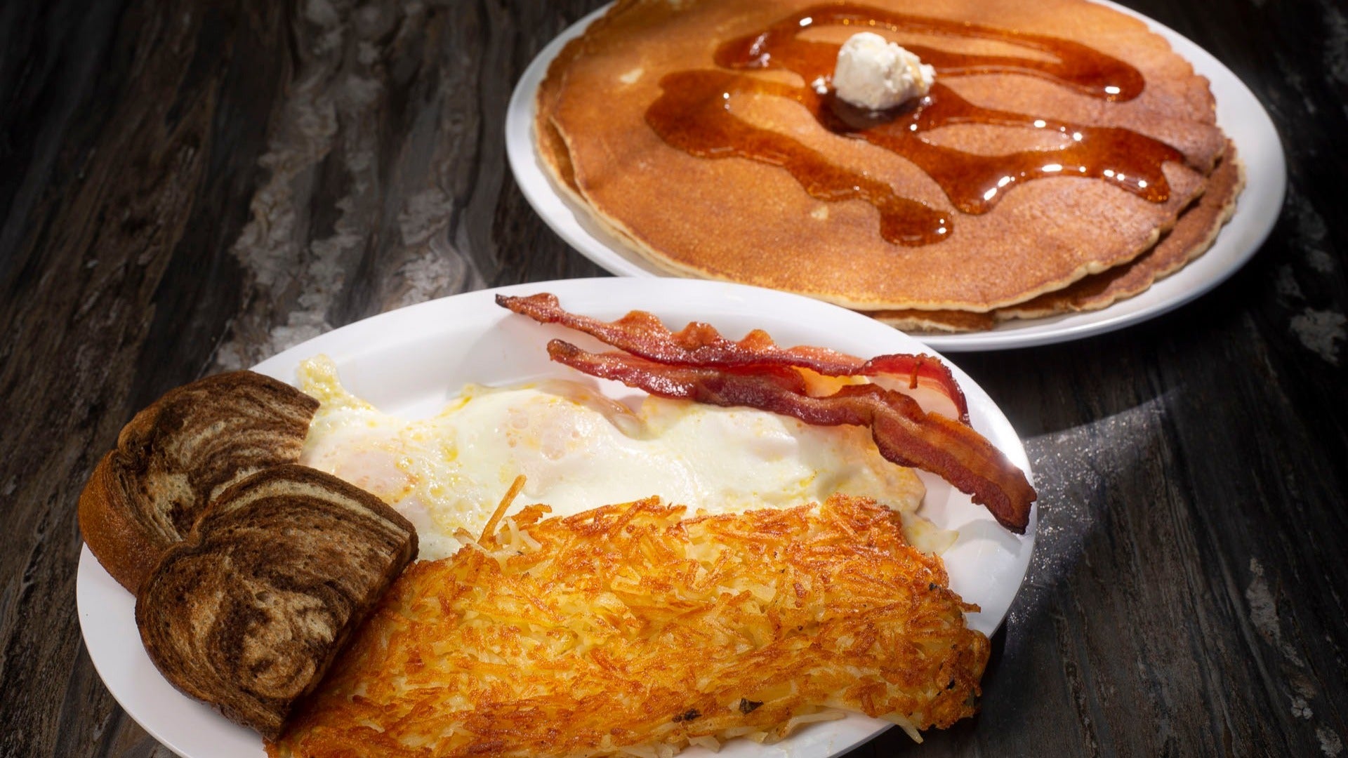 pancakes, eggs, cinnamon rolls, bacon breakfast platter