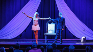 a magician and a girl performing a trick on stage